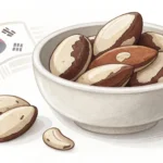 A small Korean ceramic bowl filled with shelled Brazil nuts, viewed from above on a neutral surface.