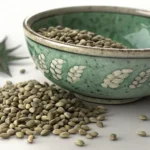 A close-up view of hemp seeds in a traditional Korean celadon bowl on a wooden surface, representing...