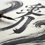A traditional Korean calligraphy brush lies next to bold, expressive black ink strokes on textured H...