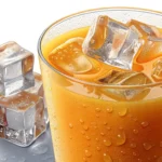 A close-up photo of a glass brimming with orange juice and ice cubes, showing condensation, placed o...
