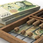 A Korean wooden abacus sits beside stacks of South Korean Won currency, symbolizing learning about K...